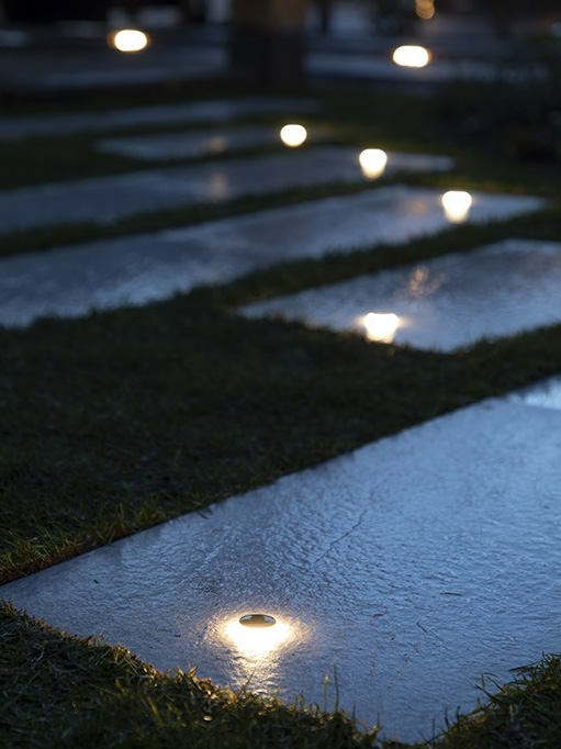 Puck light illuminating walkway installed in patio stones
